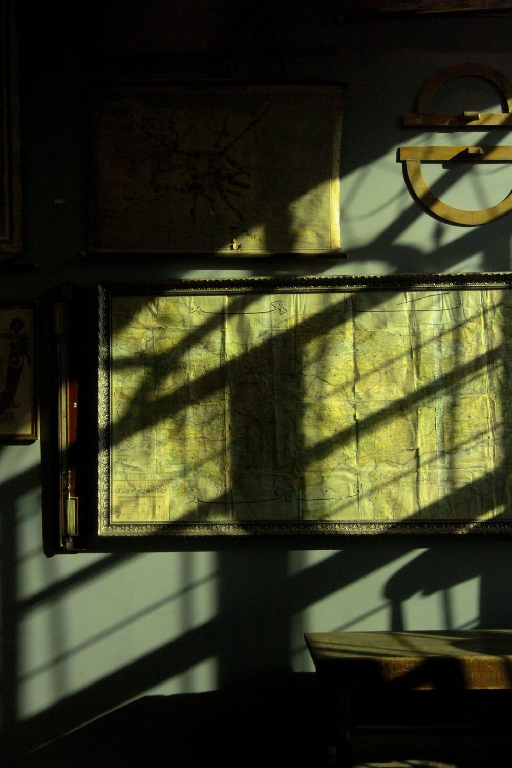 An old framed map on a wall, crossed by window light